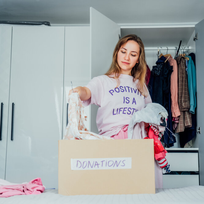 Woman Selecting Clothes from her Closet for Donating to a Charity Shop. Decluttering, Sorting Clothes, and cleaning up. Reuse, Second-hand Concept. Conscious Consumer, Sustainable Lifestyle.